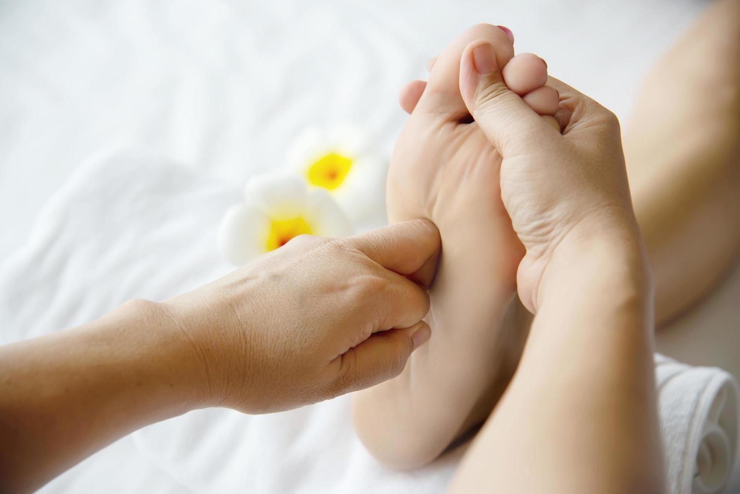 Woman receiving foot massage service from masseuse close up at hand and foot - relax in foot massage therapy service concept photo