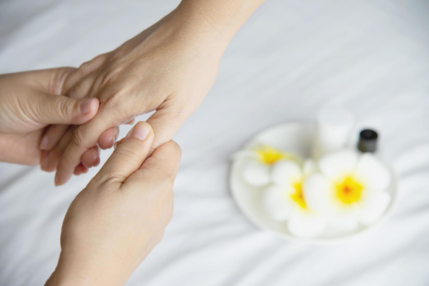 masaje de spa de manos sobre fondo de cama blanca y limpia - la gente se relaja con el servicio de masaje de manos foto