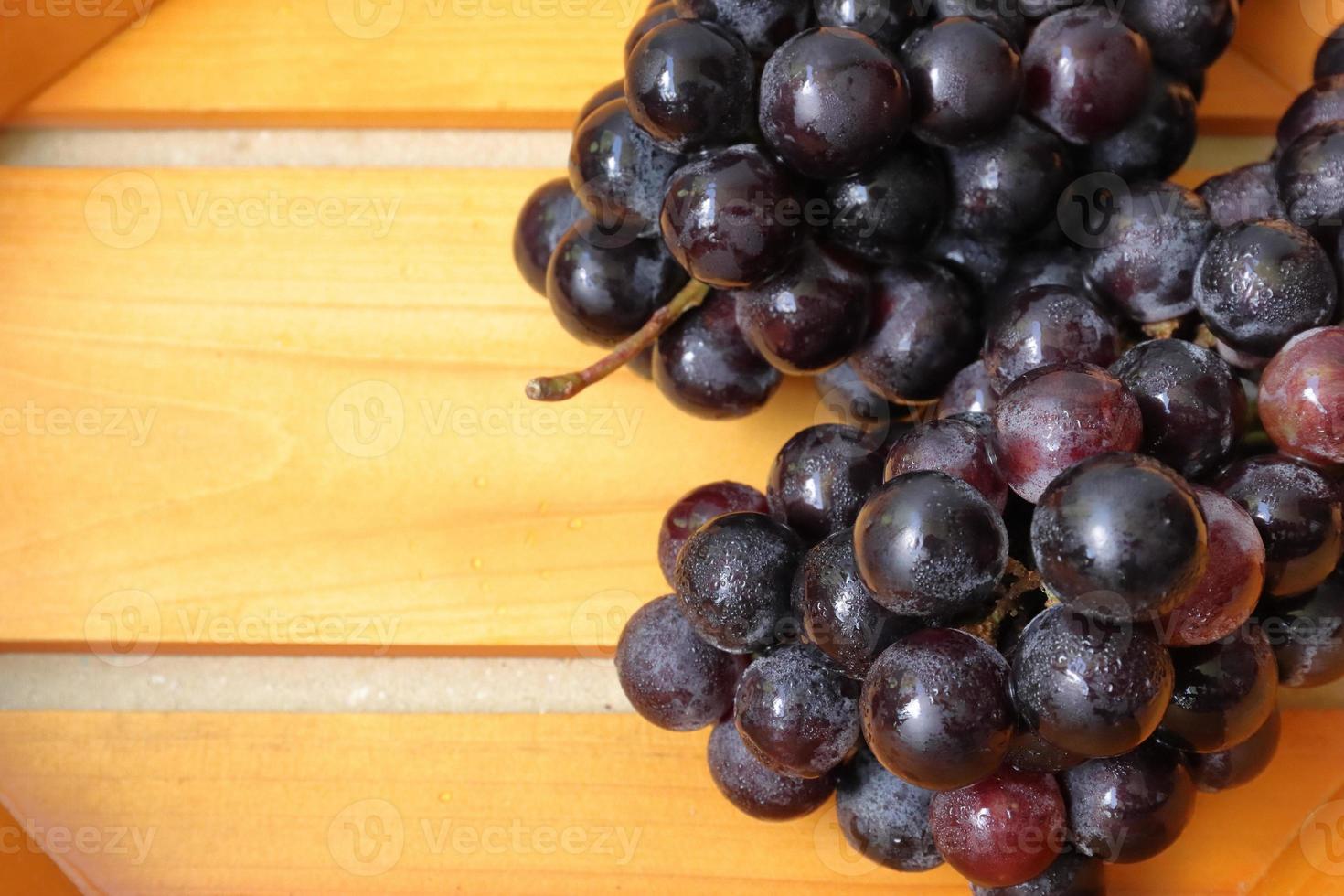 Clusters of ripe purple grapes in wooden background photo