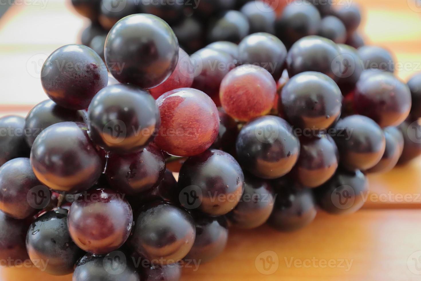 Clusters of ripe purple grapes on wooden background. Pile of fresh red and black grapes as a background. Health Fruits photo