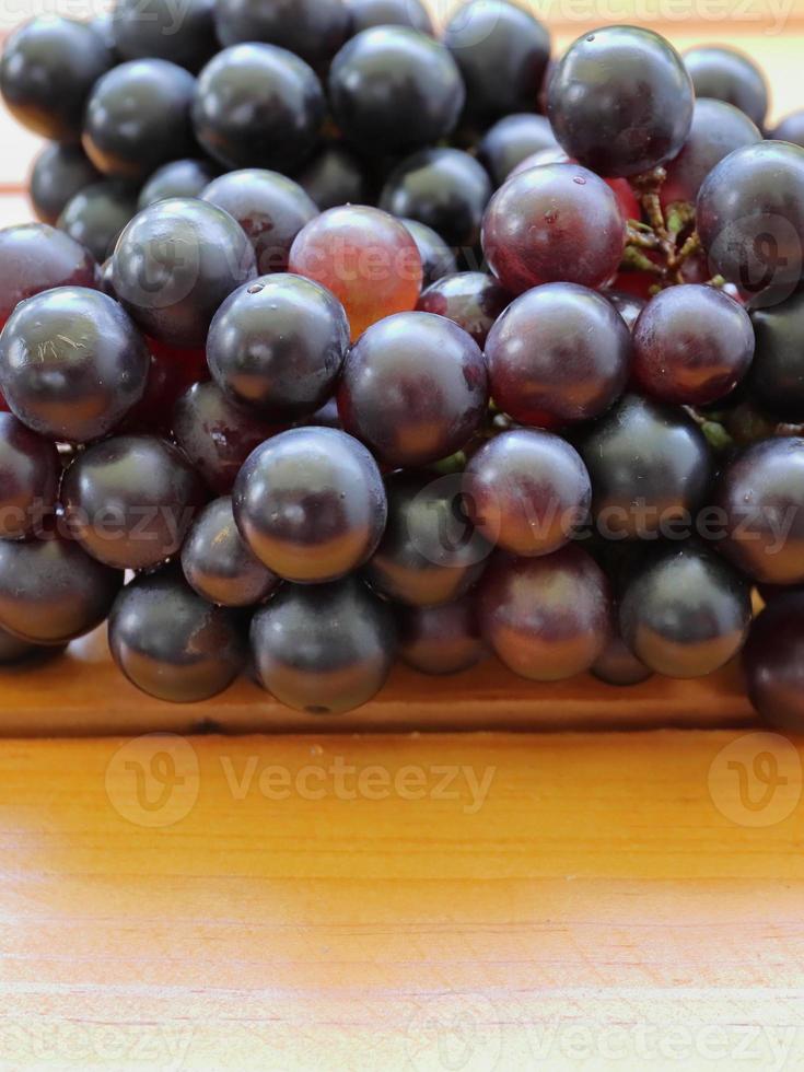 Clusters of ripe purple grapes on wooden background. Pile of fresh red and black grapes as a background. Health Fruits photo