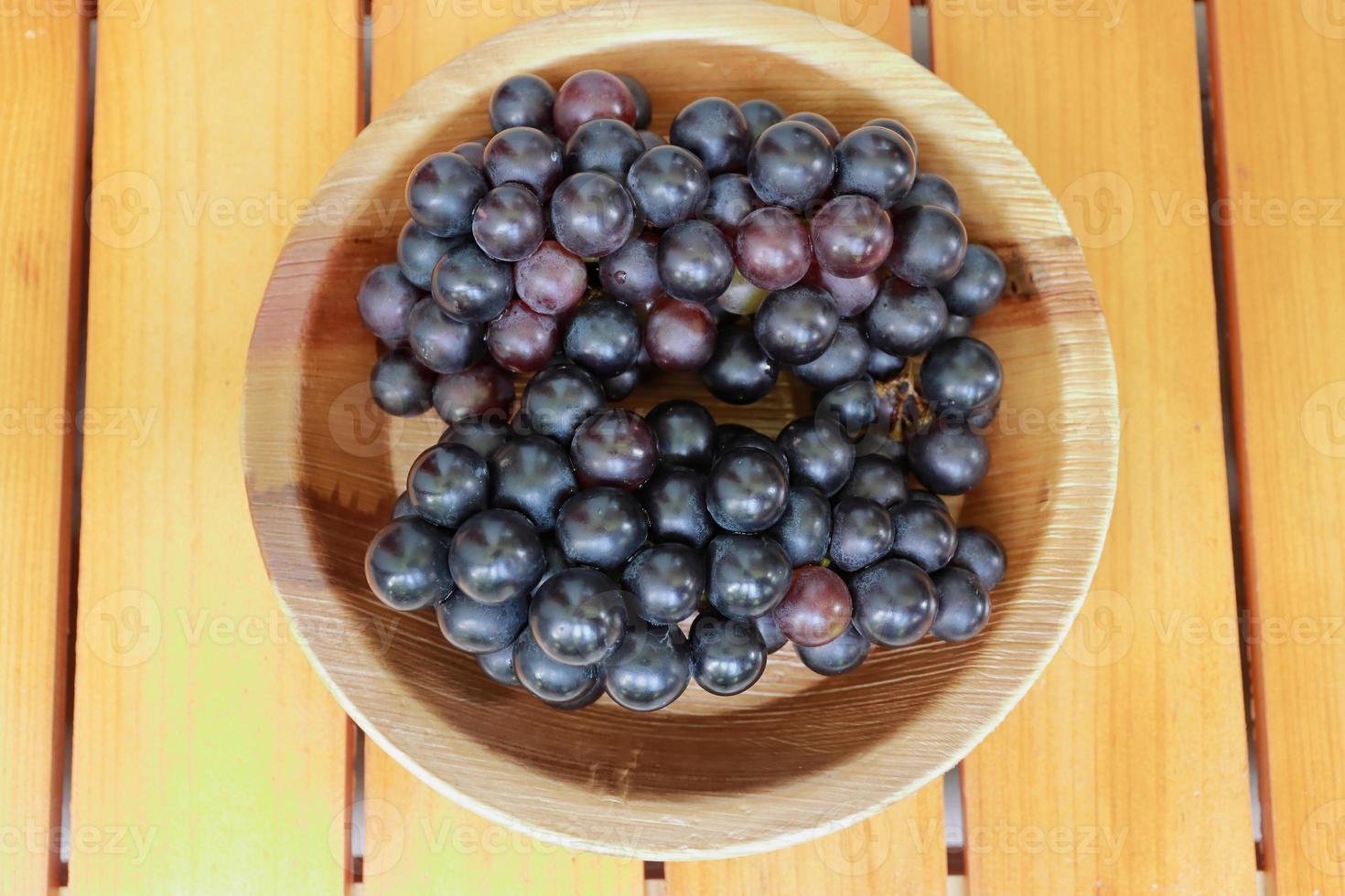 Clusters of ripe purple grapes on wooden background photo