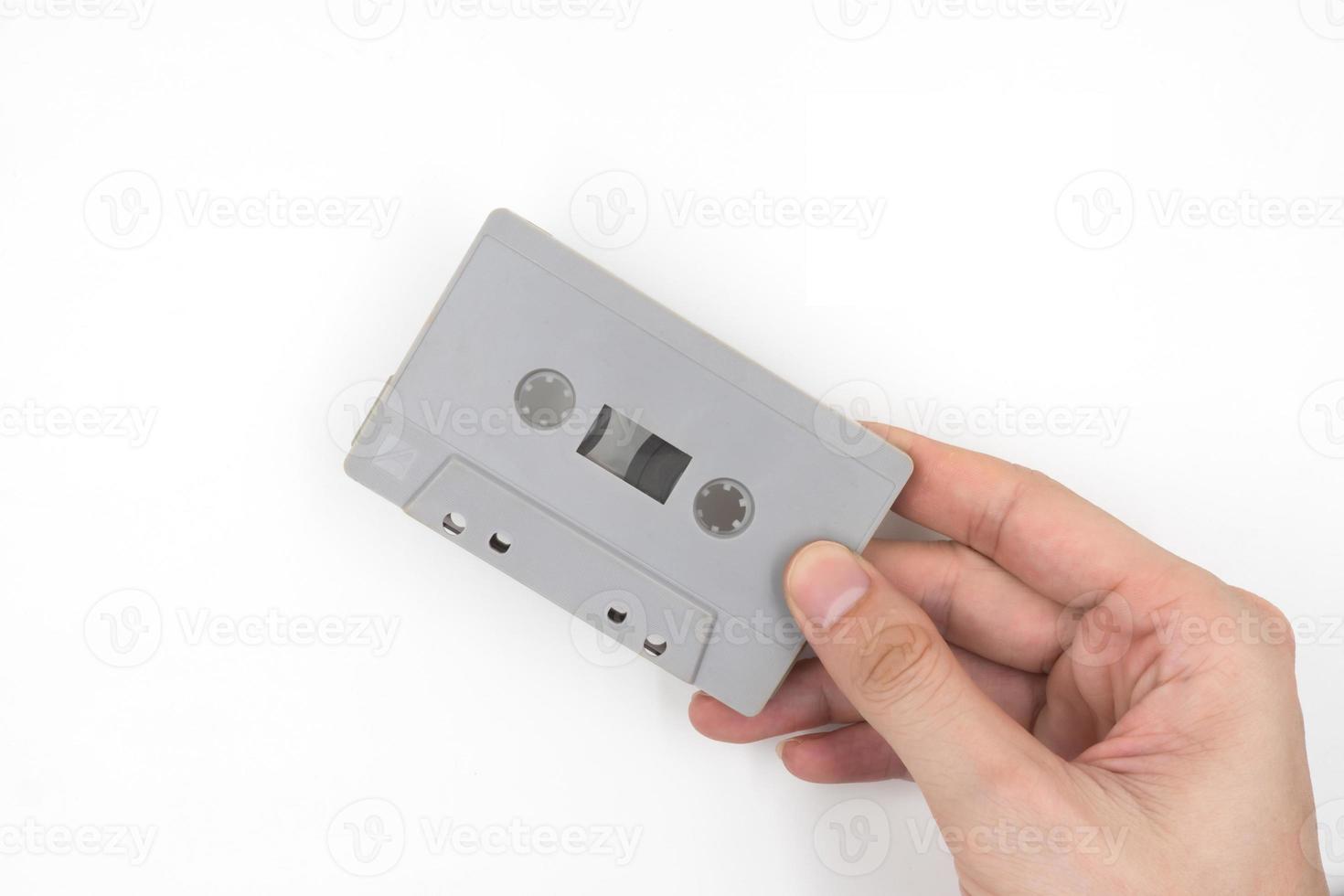 Hand holding cassette tape on white background. photo