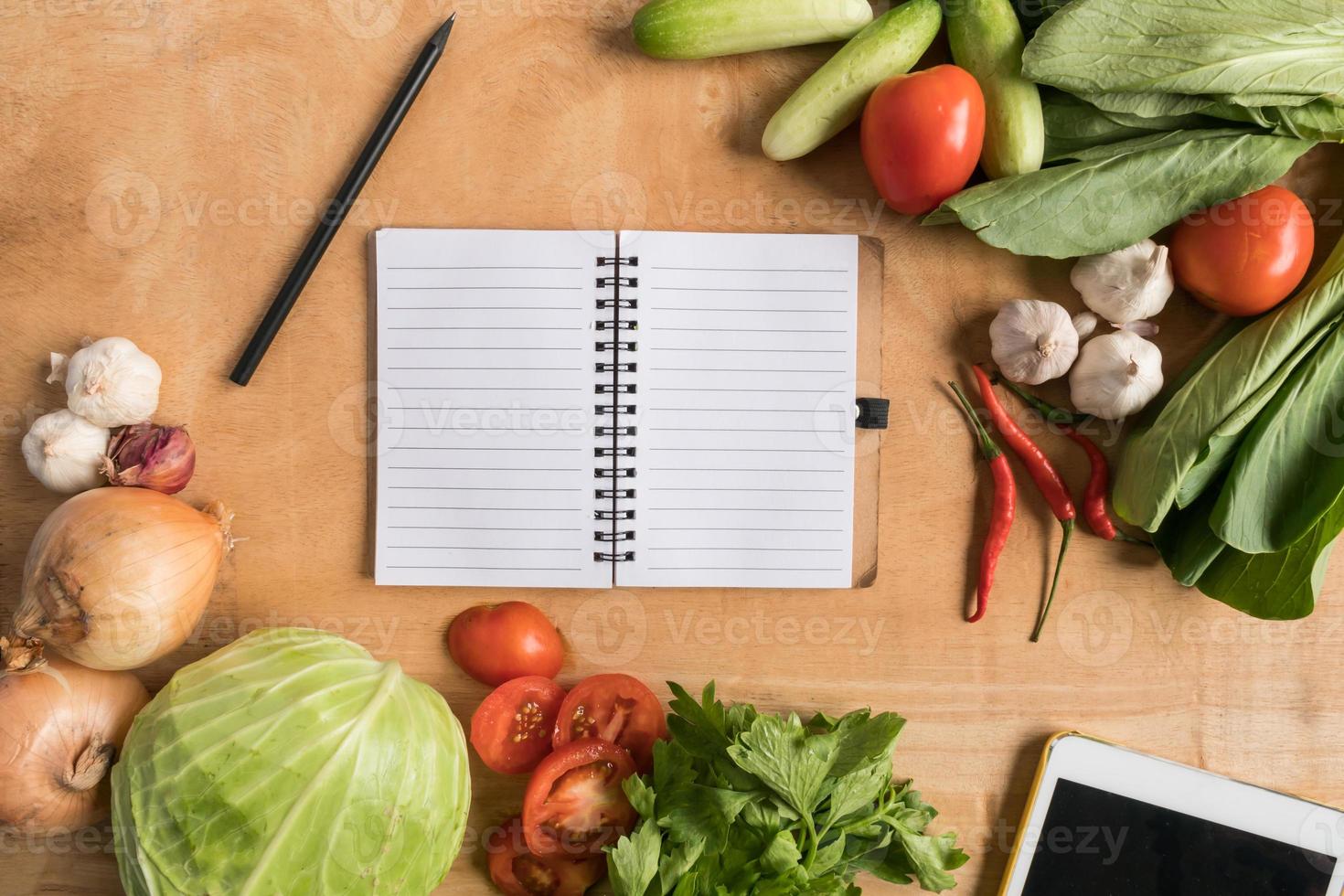 vista superior de verduras frescas con cuaderno en blanco sobre fondo de mesa de madera. foto