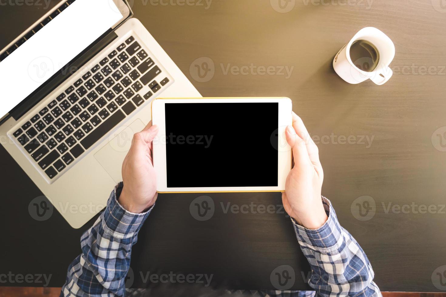 Top view of Male hands using Tablet, Laptop with Cup of coffee on the desk. photo