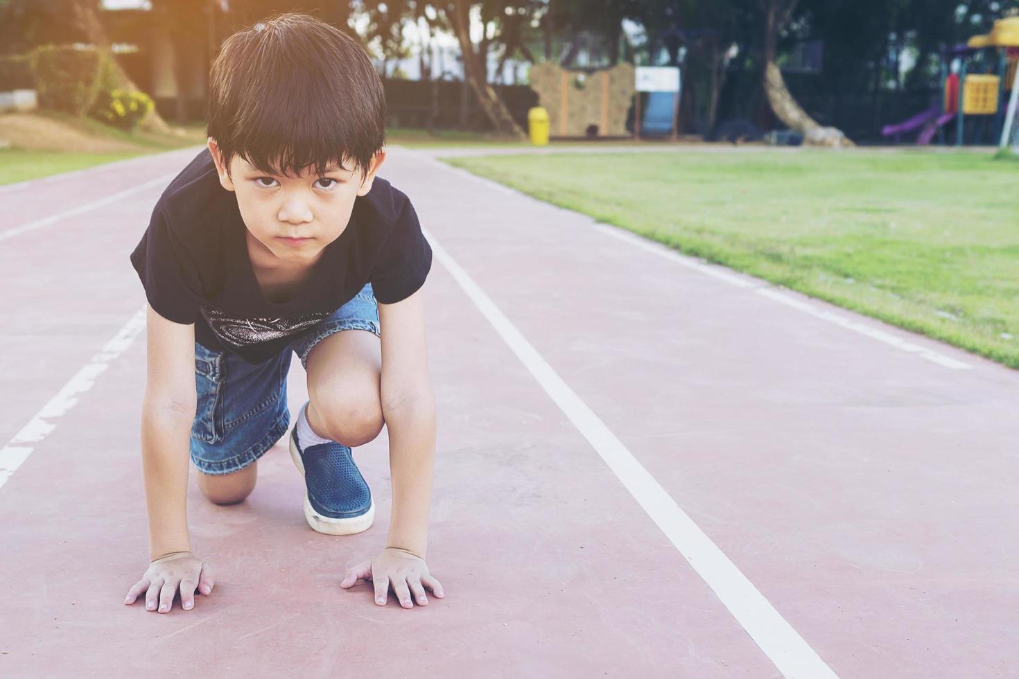 Healthy school boy ready to run at start point, active competition concept photo