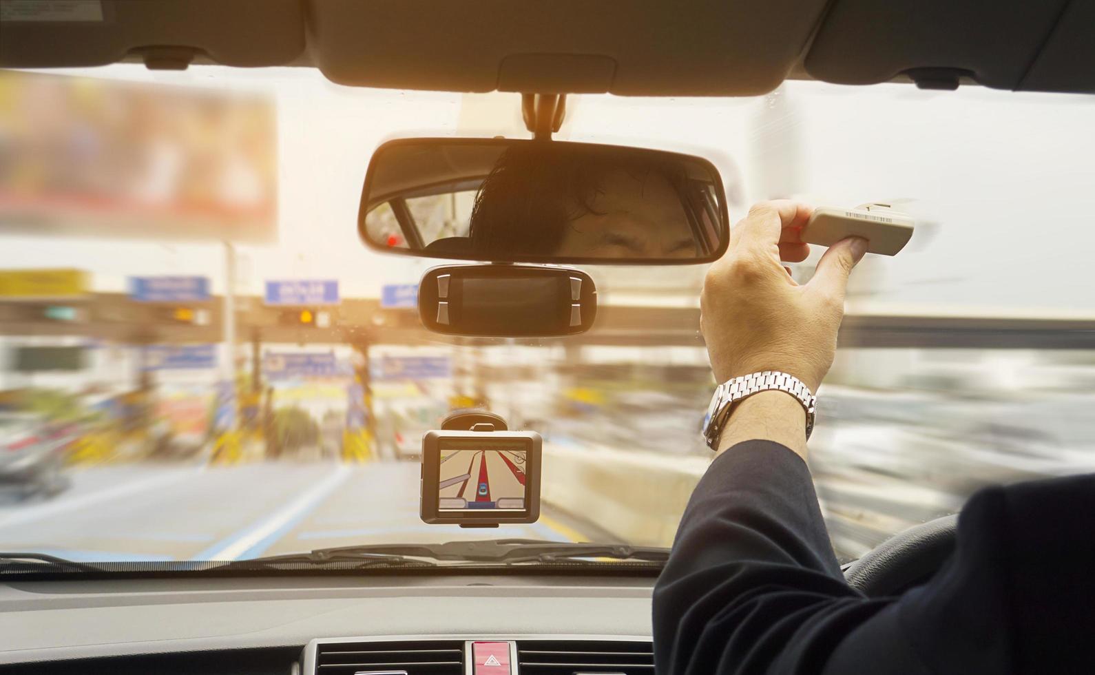 hombre conduciendo un automóvil usando el navegador y sosteniendo un dispositivo de sistema de cobro de peaje electrónico foto