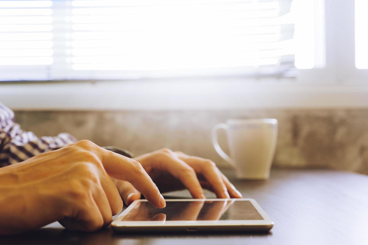 Close up of male hands using Tablet on the desk,toned with sunlight. photo