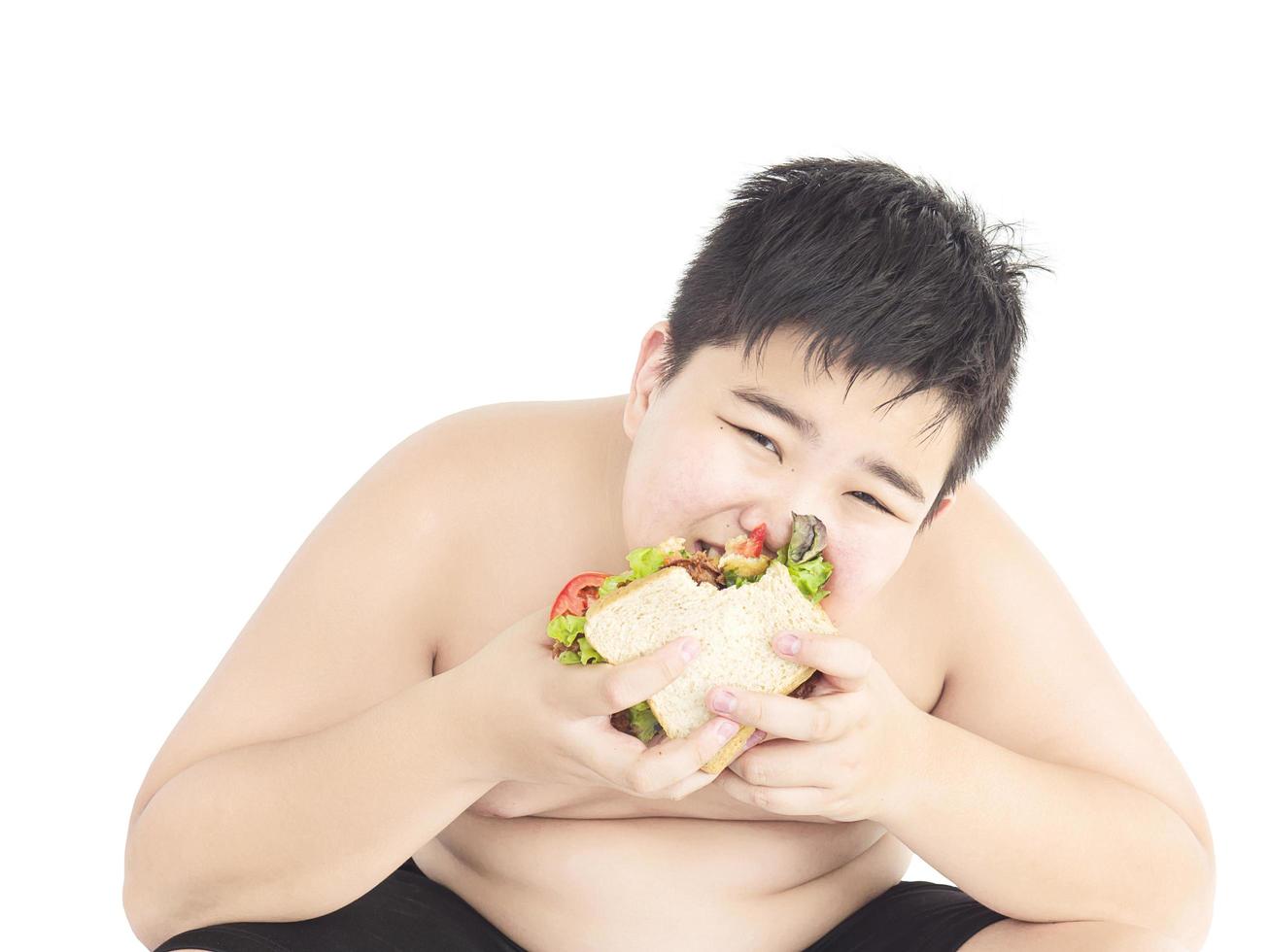 A fat boy is happily eating sandwich. photo