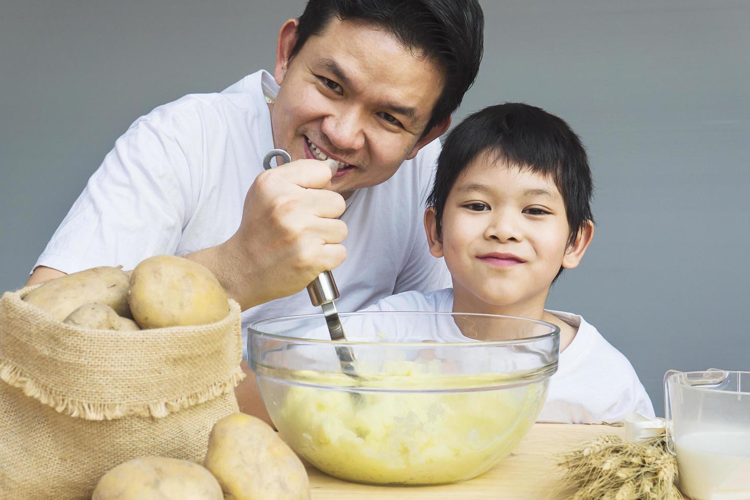 Daddy and son making mashed potatoes happily photo