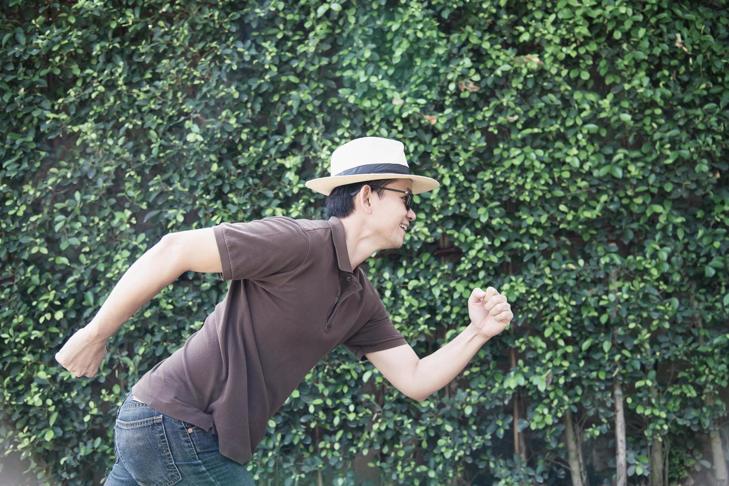 Portrait Asian tourist man over green tree wall background - tourist advertising travel concept photo