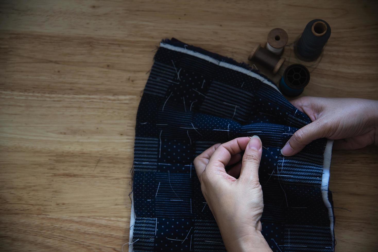 mujer vintage cosiendo tela a mano con bordados sobre fondo de mesa de madera - gente y concepto de tareas domésticas hechas a mano foto