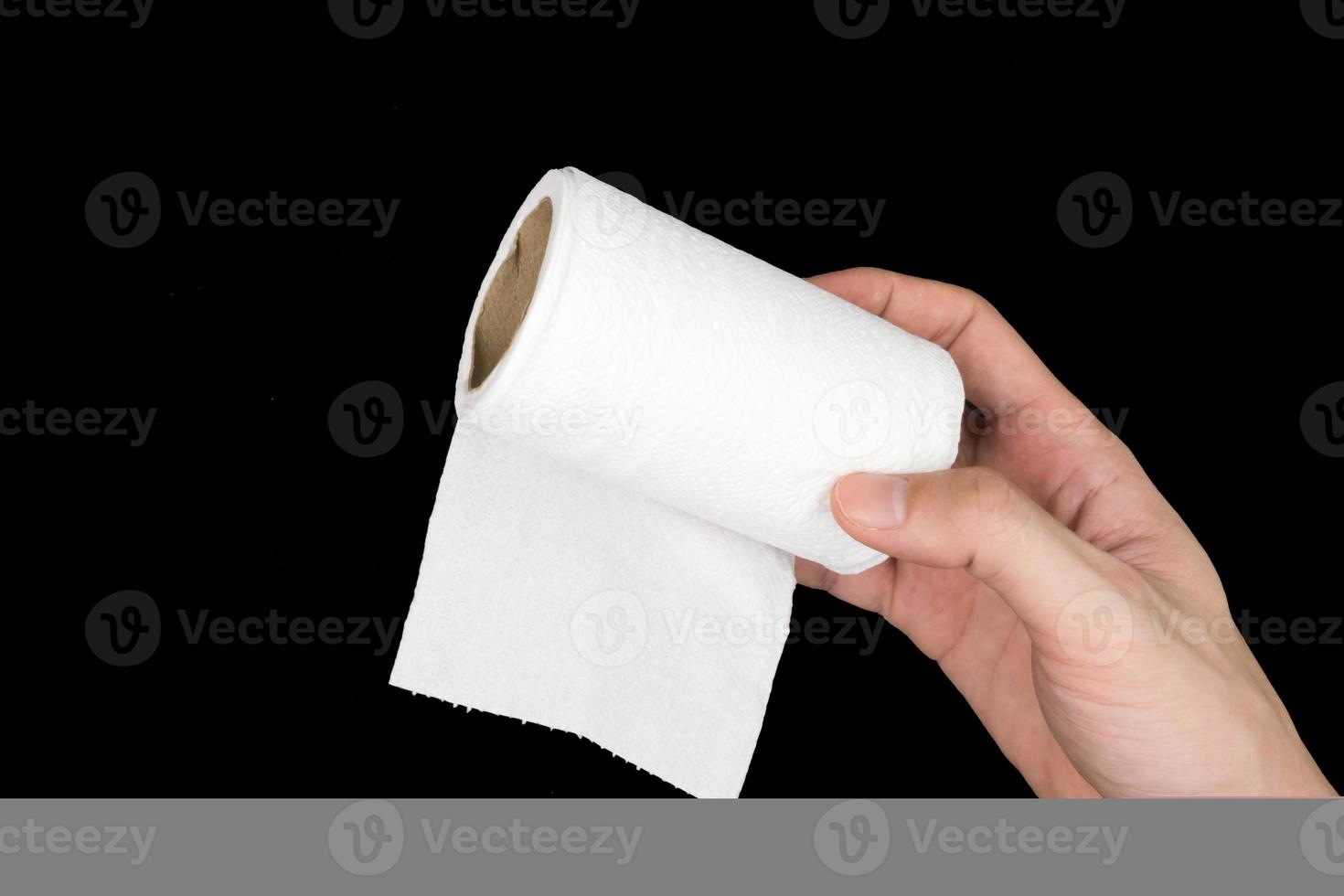 Toilet paper roll with hand on black background. photo