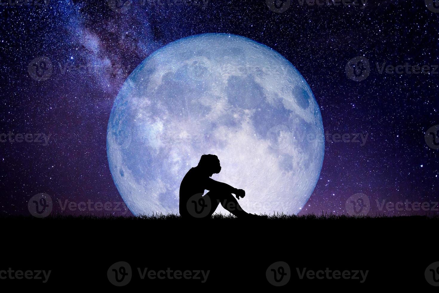 Desperate and lonely man in the background of the moon at night. Desperate, heartbreaking, and lonely concepts photo