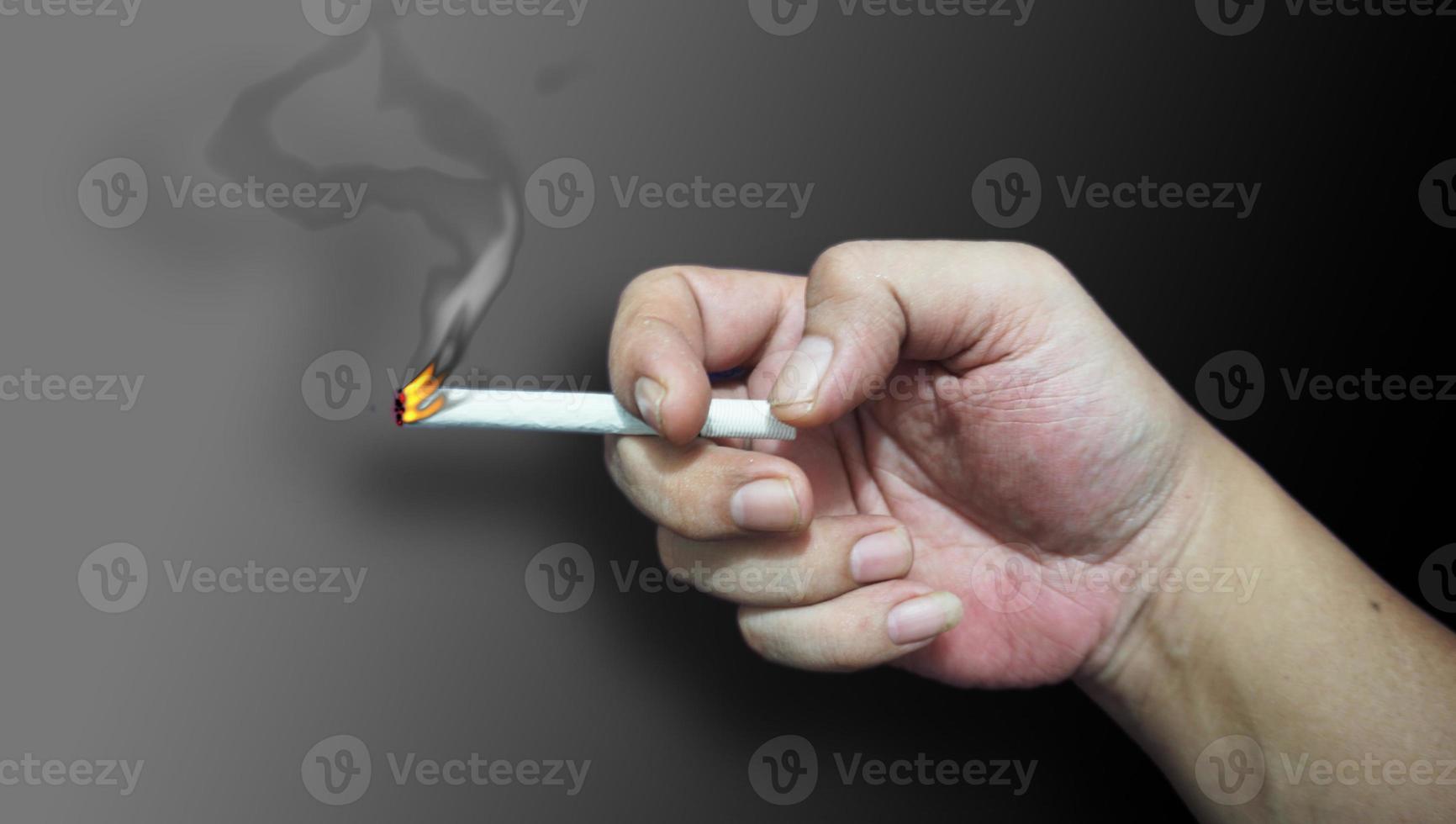 Hands hold the cigarette with smoke in isolate color background. photo