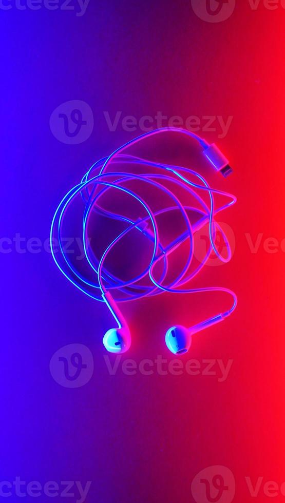 Earphones, Earbud type white color and Cloud symbol made from cable isolated on blue and red gradient background, with copy space photo