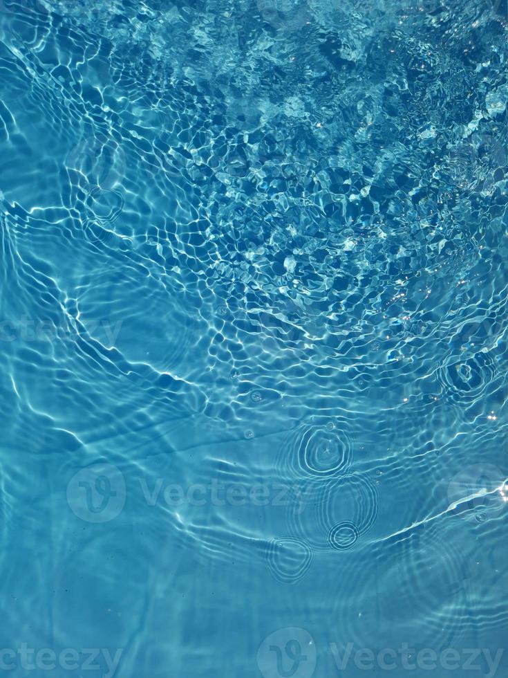 desenfoque de agua azul borrosa que brilla en el mar. fondo de detalle de agua ondulada. la superficie del agua en el mar, fondo del océano. ola de agua bajo el fondo de la textura del mar. foto