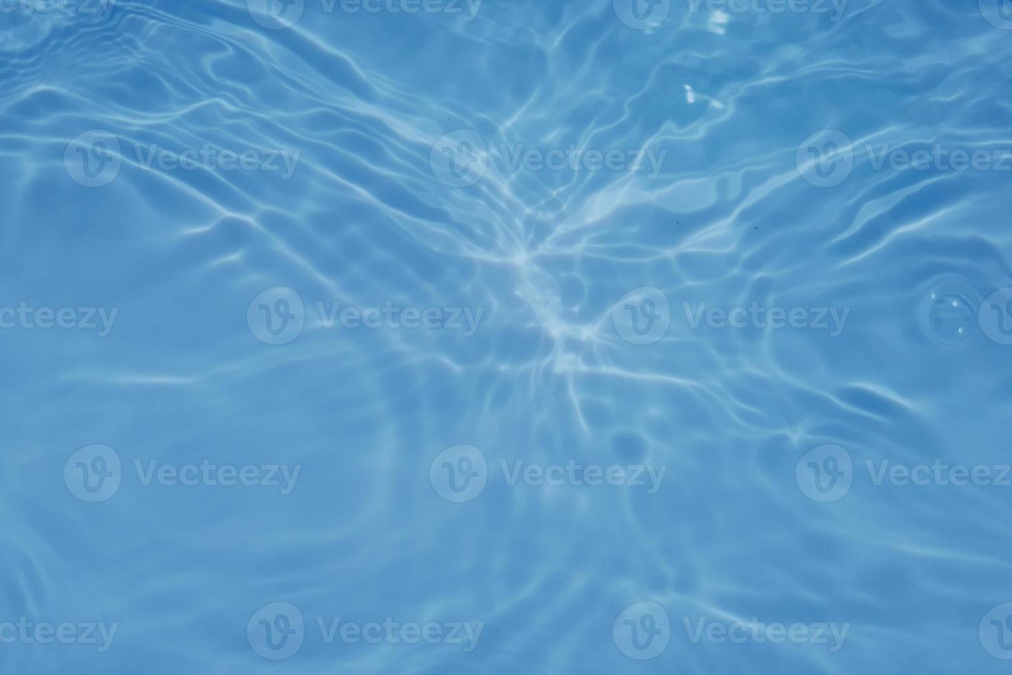Defocus blurred transparent blue colored clear calm water surface texture with splashes and bubbles. Trendy abstract nature background. Water waves in sunlight with copy space. Blue watercolor texture photo
