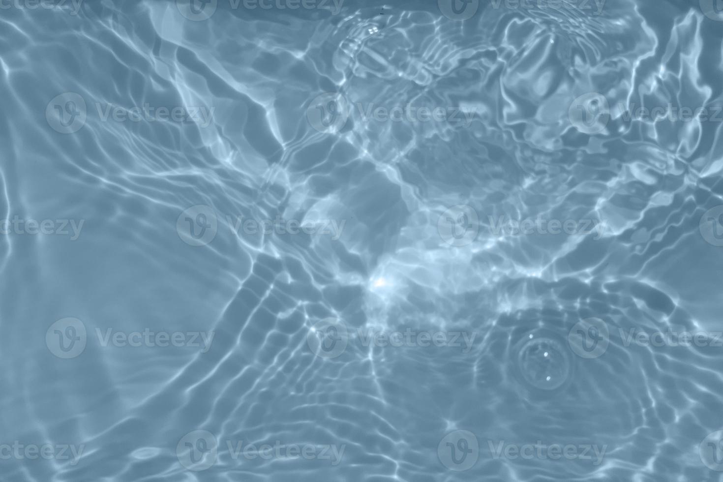 Defocus blurred transparent blue colored clear calm water surface texture with splashes and bubbles. Trendy abstract nature background. Water waves in sunlight with copy space. Blue watercolor texture photo