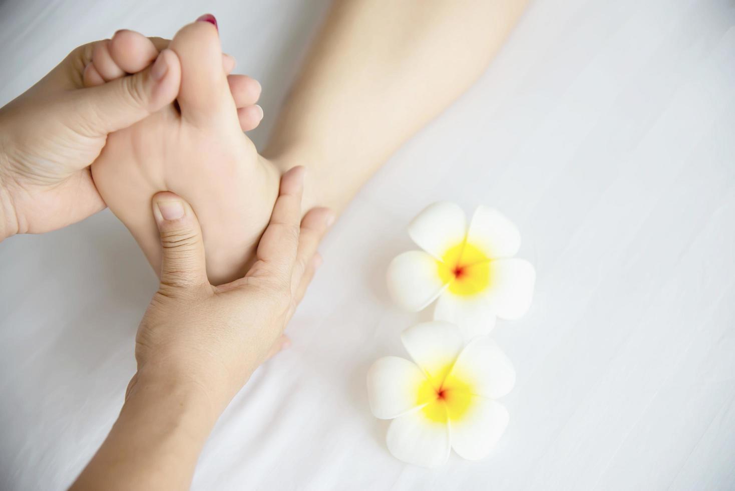 Woman receiving foot massage service from masseuse close up at hand and foot - relax in foot massage therapy service concept photo