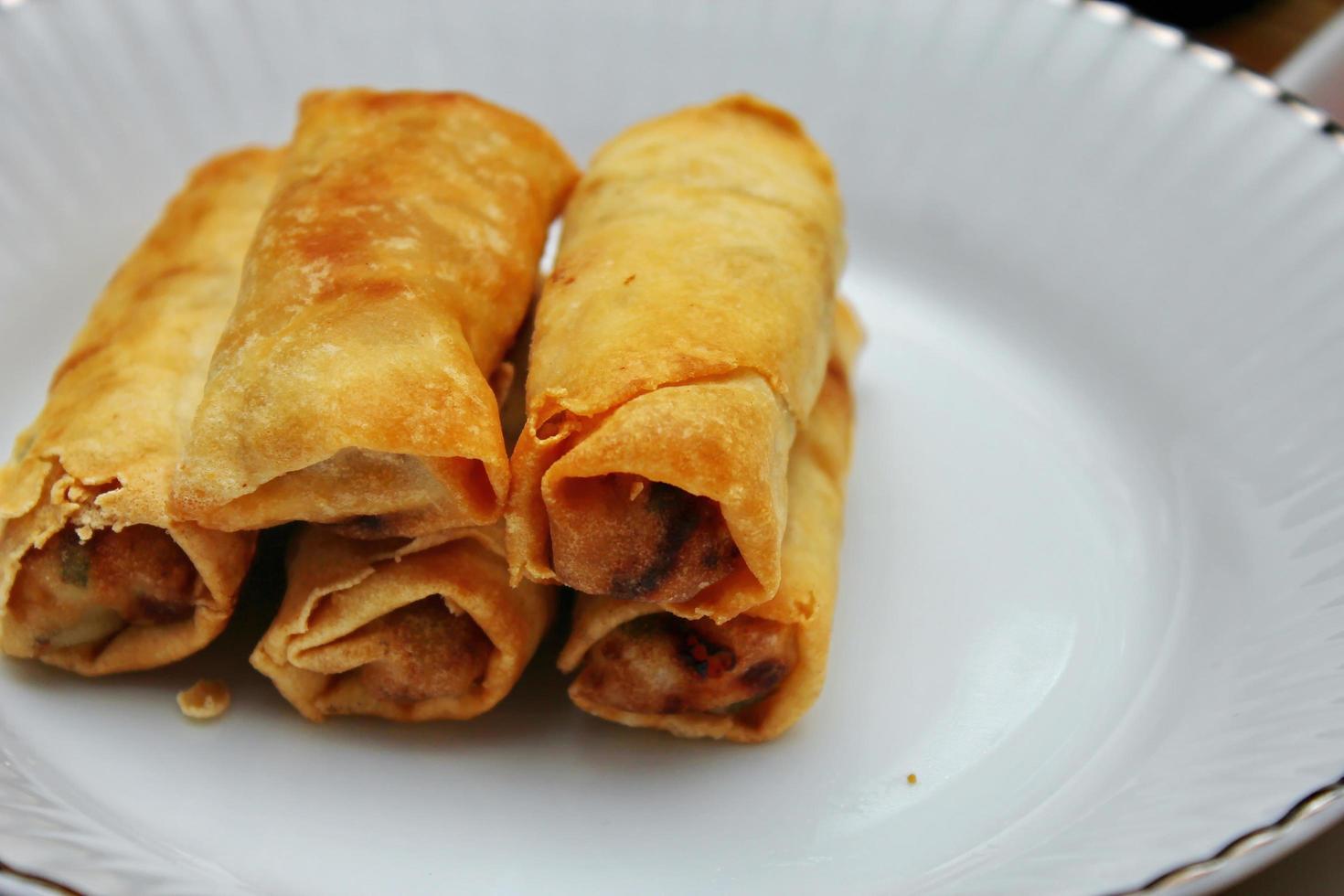 Fried spring rolls placed in a white plate, fried spring rolls are a popular Asian dish. photo