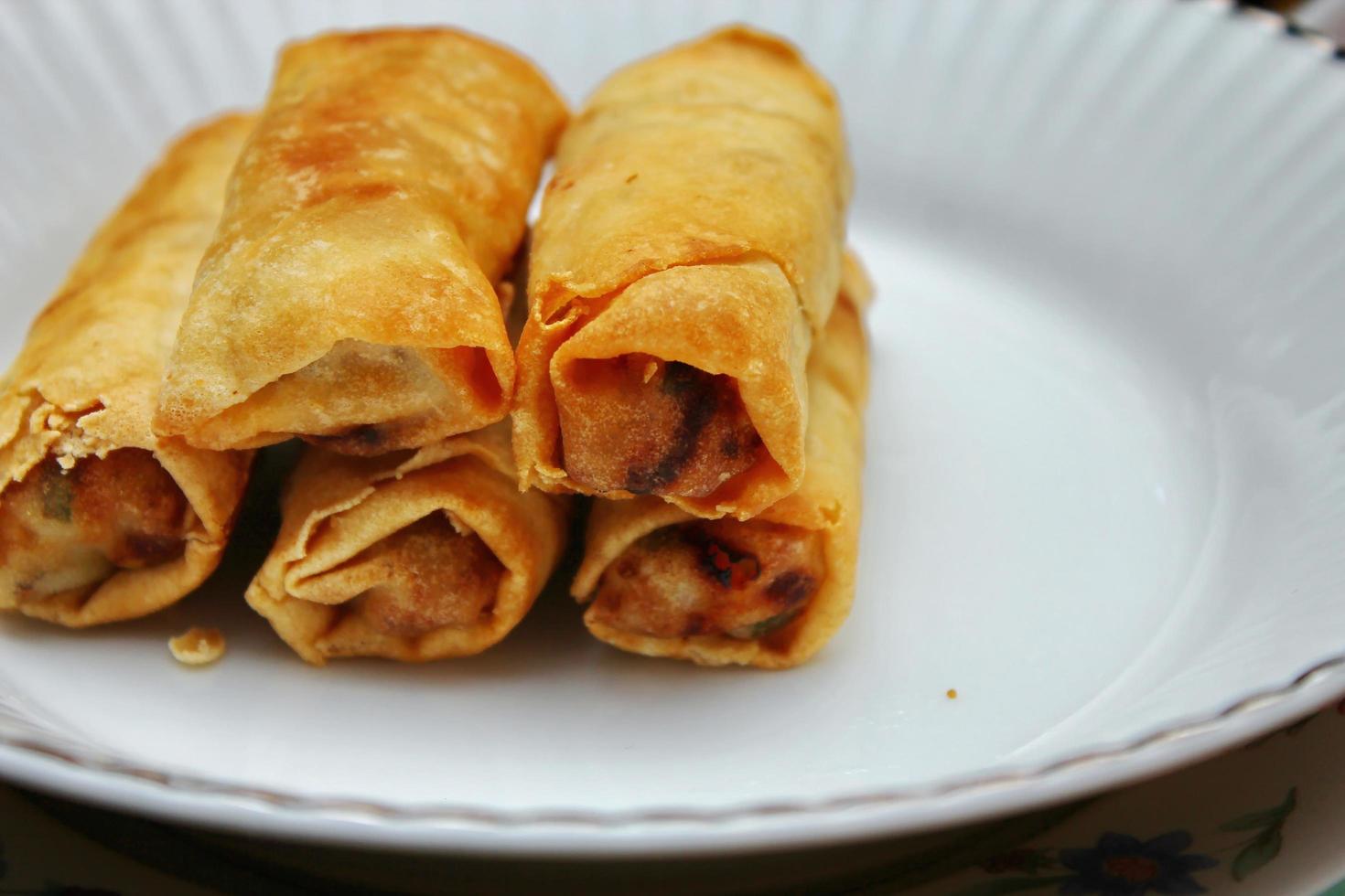Fried spring rolls placed in a white plate, fried spring rolls are a popular Asian dish. photo