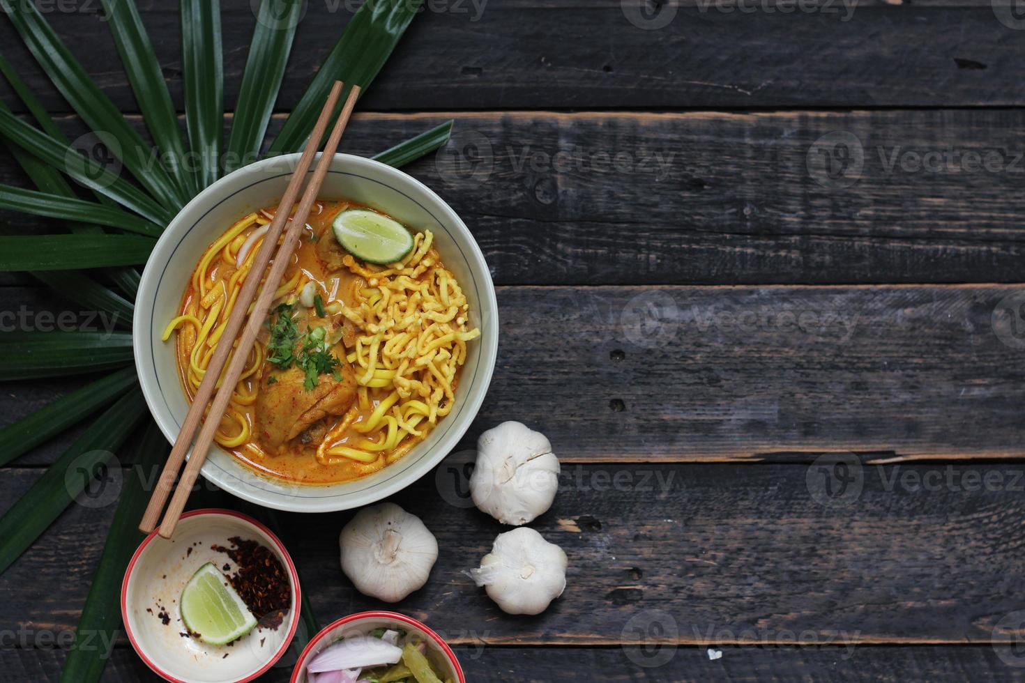 receta de khao soi, khao soi, khao soi kai, fideos tailandeses khao soi, curry de pollo con condimento servido en una mesa de madera foto