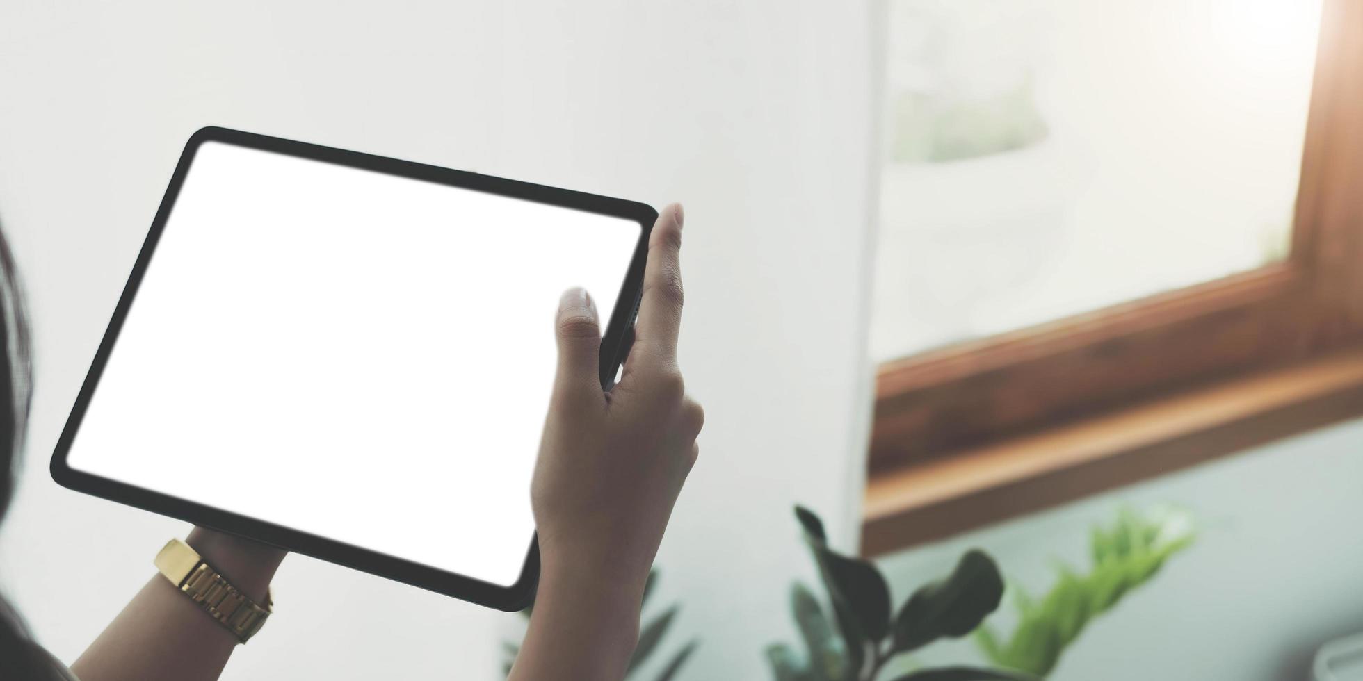 Mockup image of woman's hand holding black tablet pc with blank white screen in wooden cafe photo