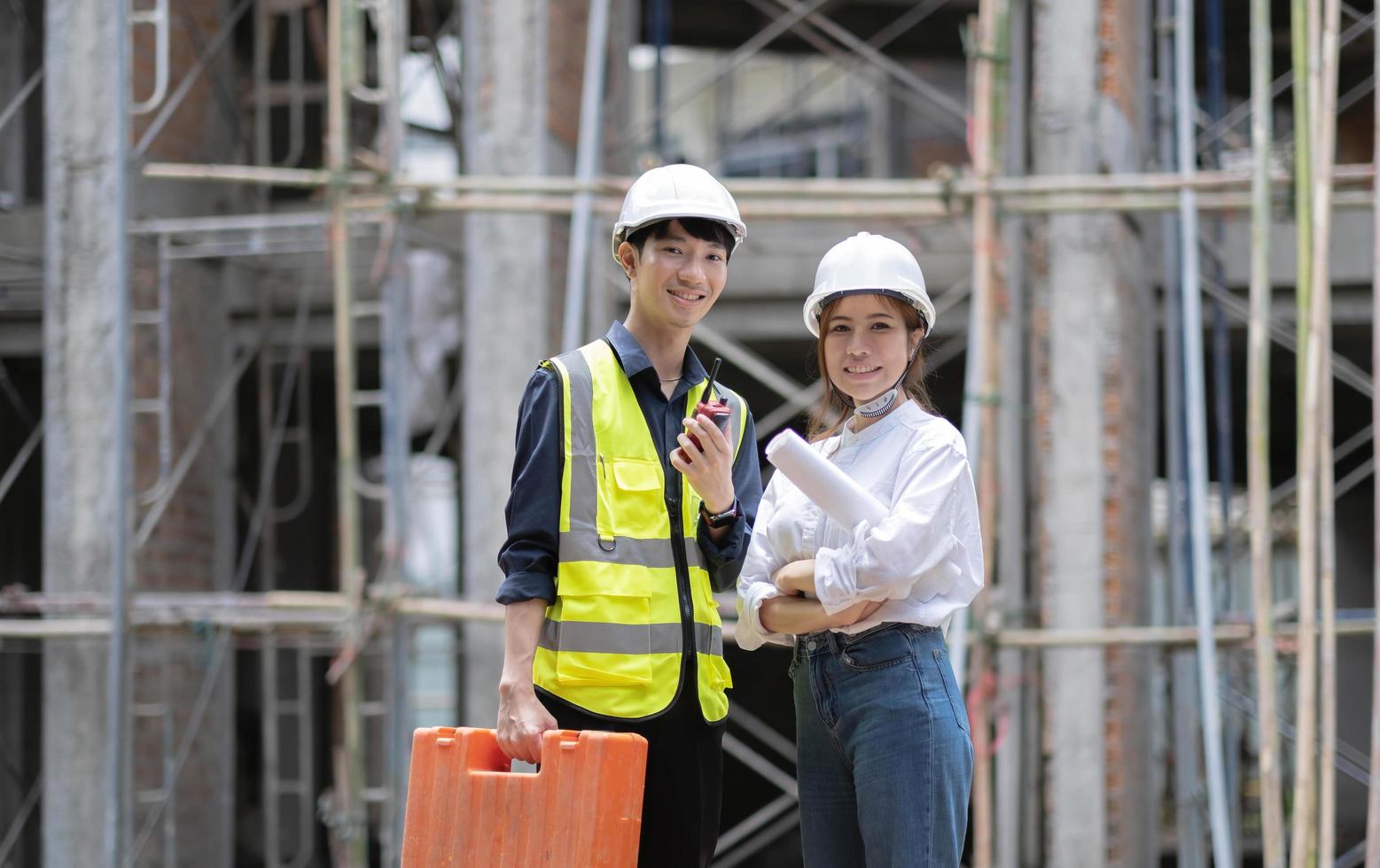 Two confident an engineers, architects or foremen standing with crossed arms pose in front of construction site as the background. photo