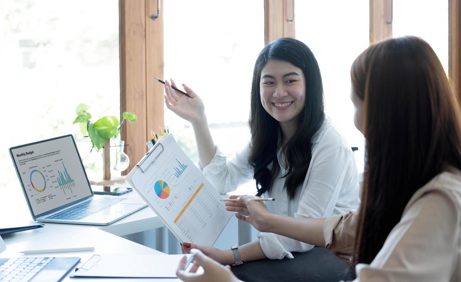 dos jóvenes empresarias asiáticas discuten el trabajo del proyecto de inversión y la estrategia de planificación. gente de negocios hablando junto con una computadora portátil en la oficina. foto