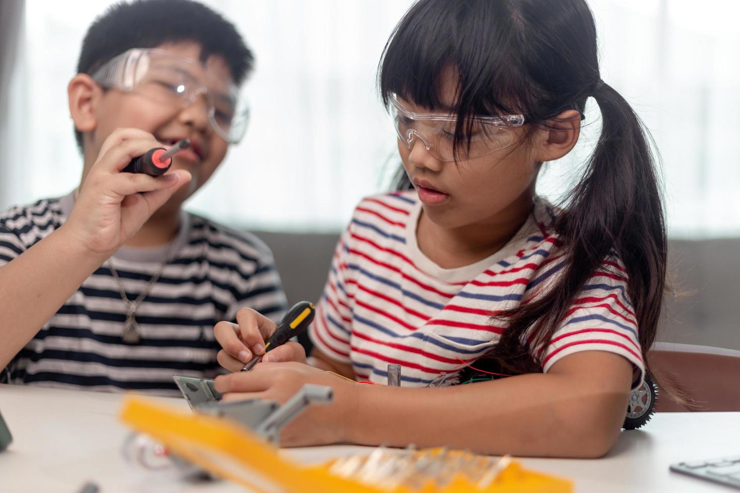 dos niños asiáticos que se divierten aprendiendo a codificar juntos, aprendiendo de forma remota en casa, ciencias madre, educación en el hogar, distanciamiento social divertido, aislamiento, nuevo concepto normal foto