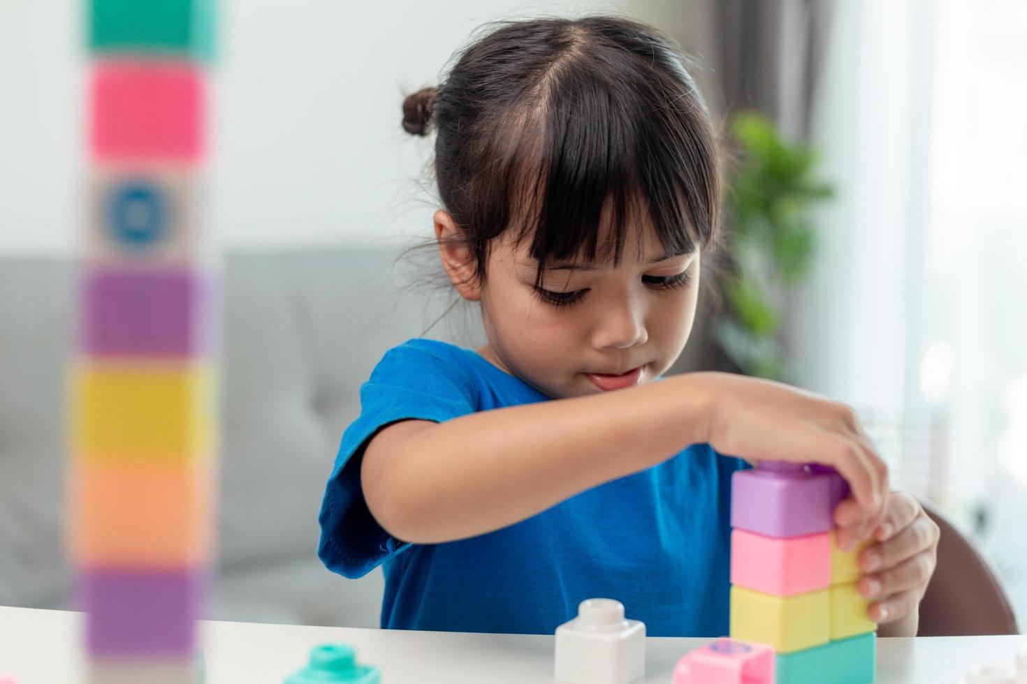 Adorable little girl playing toy blocks in a bright room photo