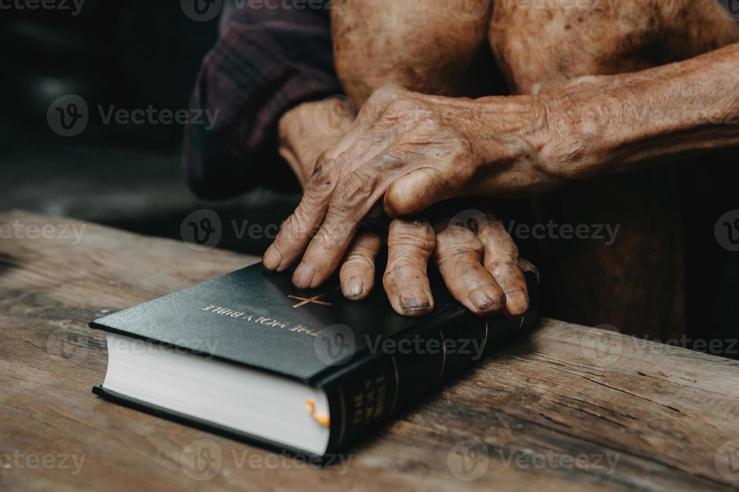 manos juntas en oración a dios junto con la biblia en el concepto cristiano y la religión, el anciano ora en la biblia foto