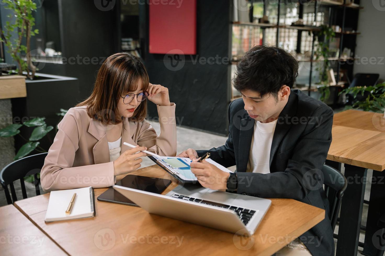 Businesswomen work and discuss their business plans. A Human employee explains and shows her colleague the results paper in office. photo