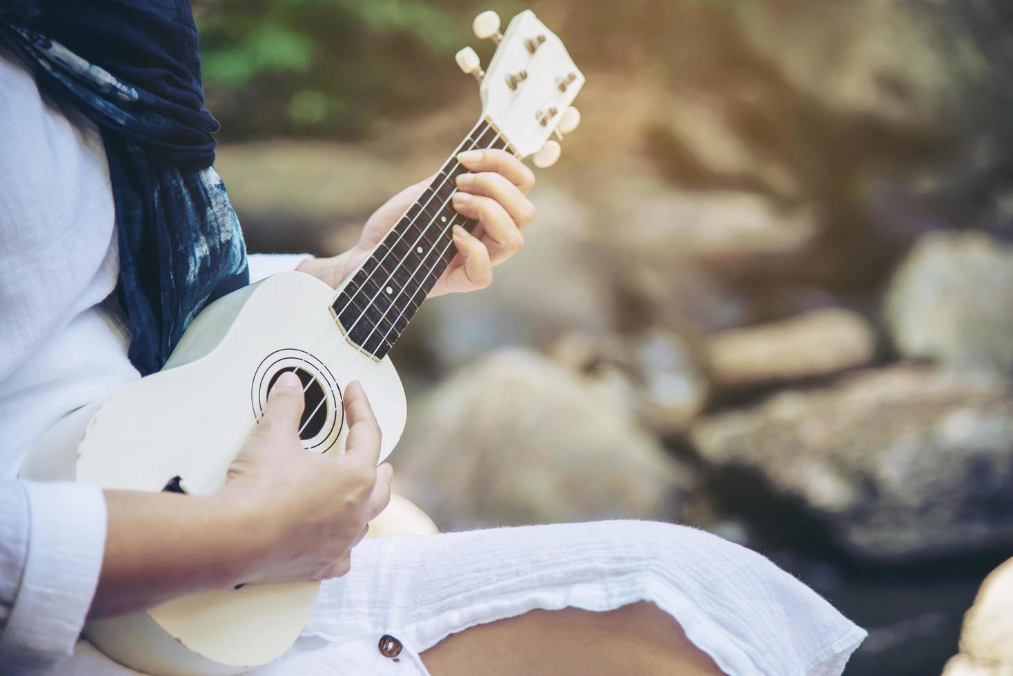 las mujeres tocan el ukelele nuevo en la cascada: la gente y el estilo de vida del instrumento musical en el concepto de naturaleza foto