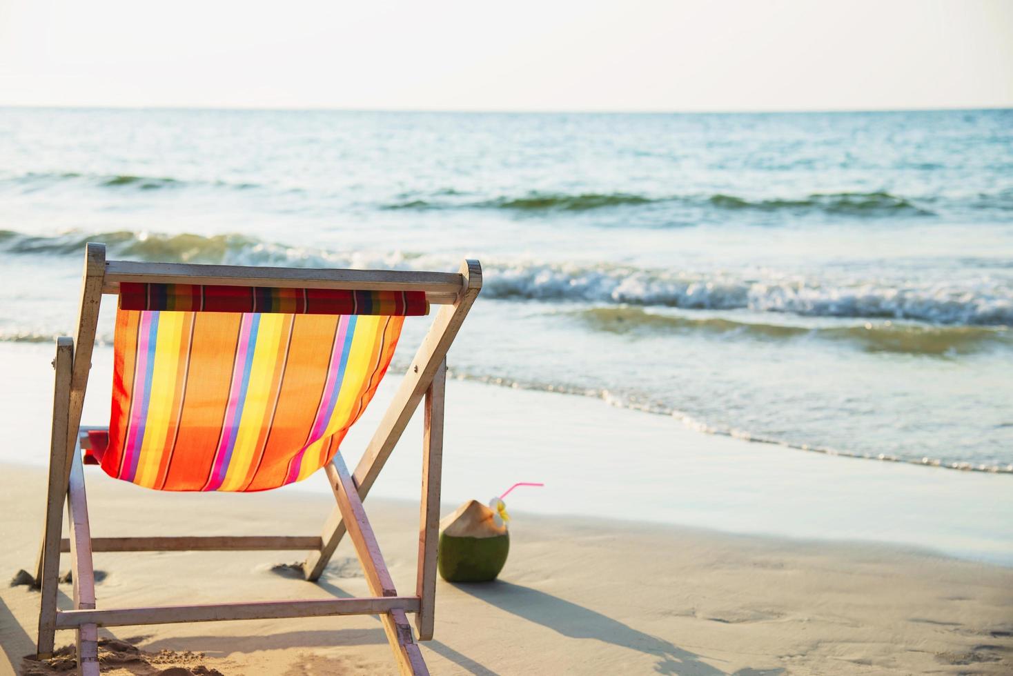 relájese en la silla de playa con piña de coco y copa de cóctel en una playa de arena limpia con mar azul y cielo despejado - concepto de relajación de fondo de naturaleza marina foto