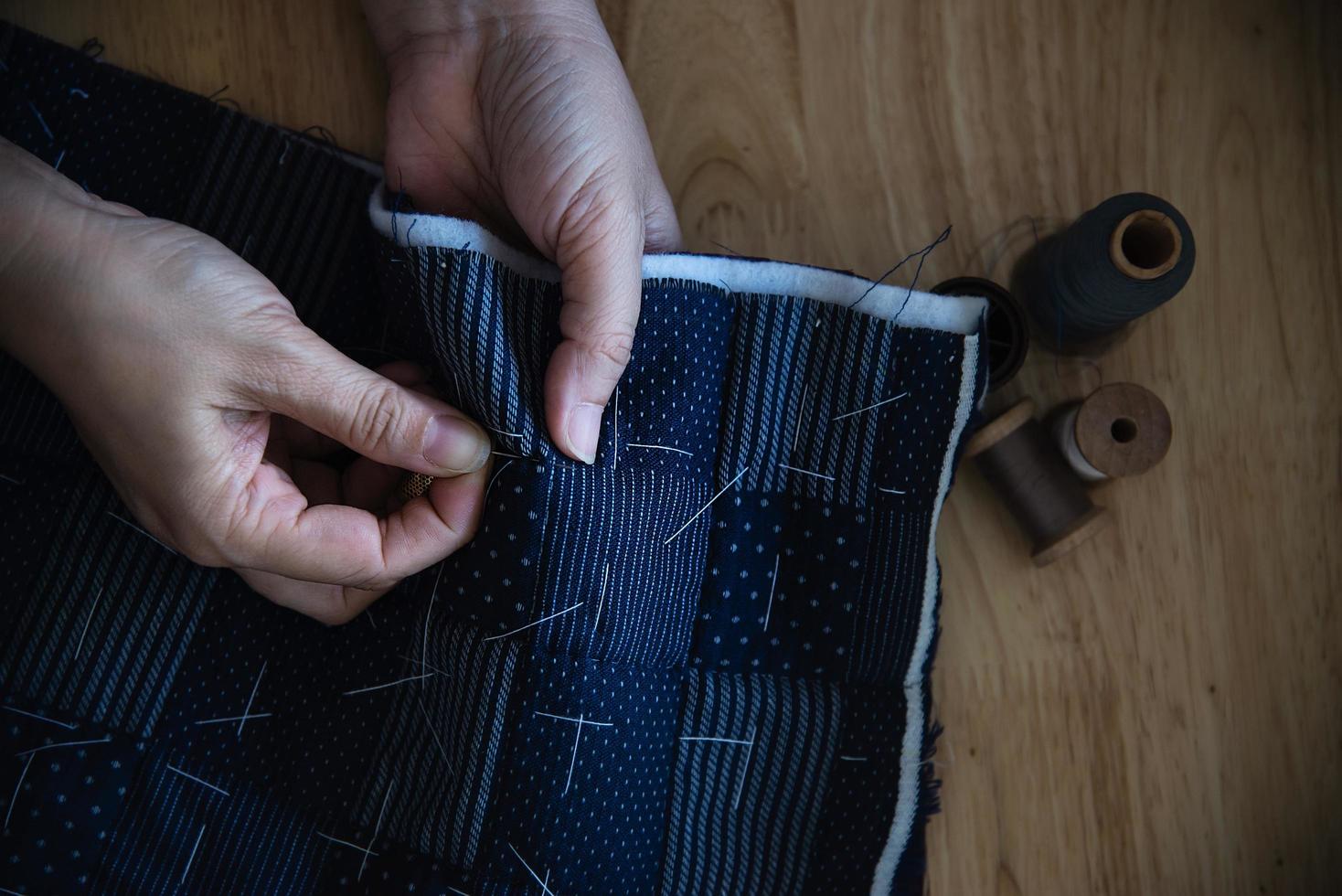 mujer vintage cosiendo tela a mano con bordados sobre fondo de mesa de madera - gente y concepto de tareas domésticas hechas a mano foto