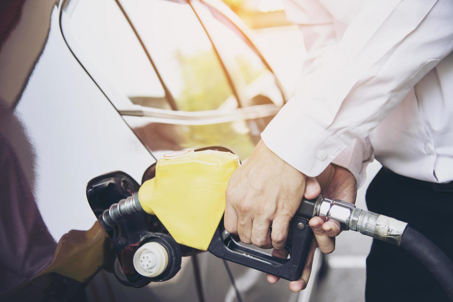 hombre poniendo gasolina en su coche en una gasolinera de bomba foto