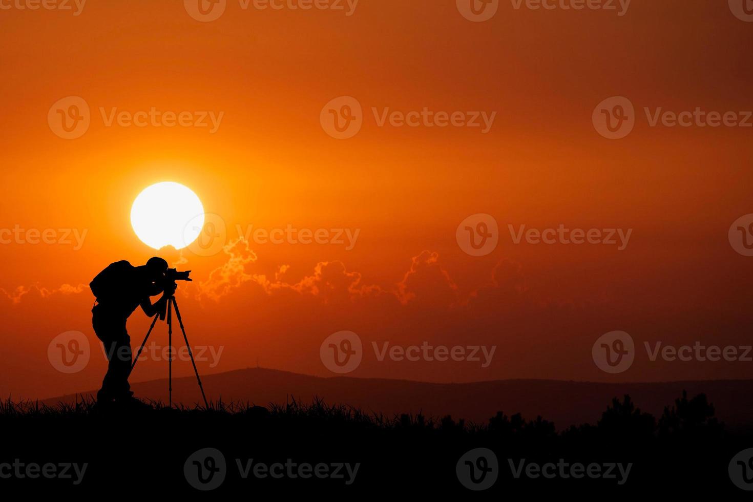 la silueta de un fotógrafo profesional se centra en disparar en un hermoso prado. foto