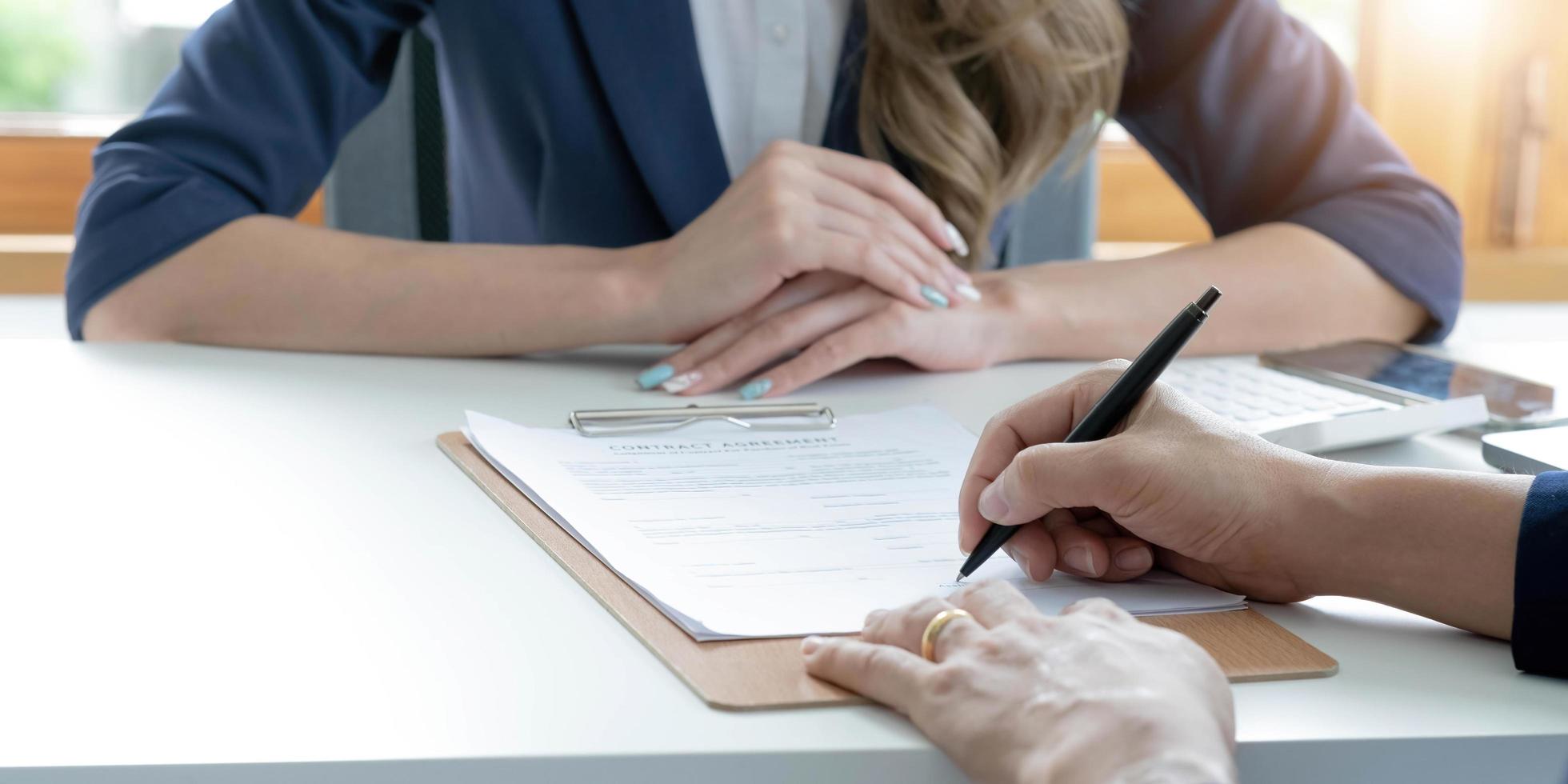 Close up of male hand putting signature, running own small business, have a contract in place to protect it, basics of writing contract, one sentence in a contract can cost a business. photo