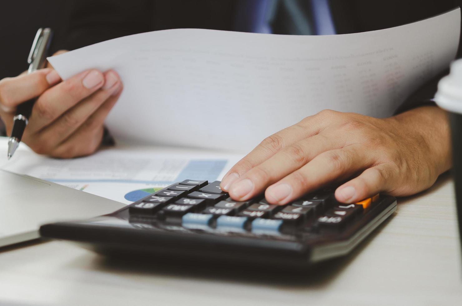 businessman holding calculators and business documents charts statistical data investment analysis and tax accounting. photo