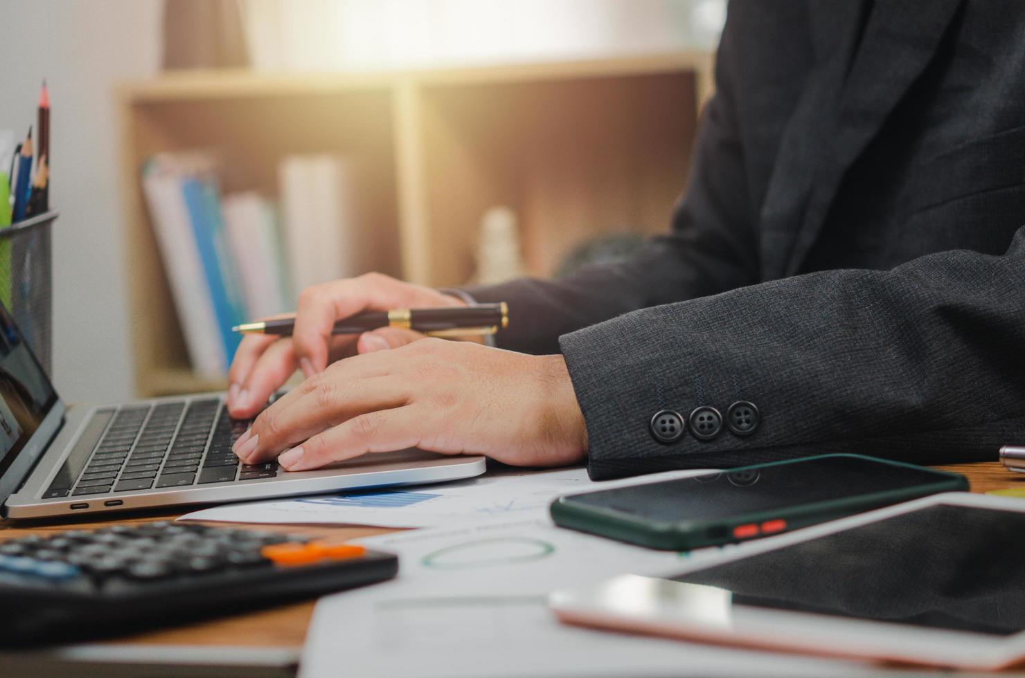 persona de negocios que señala el informe de marketing financiero del gráfico del documento y la inversión del análisis del gráfico de papeleo con la computadora portátil en el escritorio de la oficina. foto