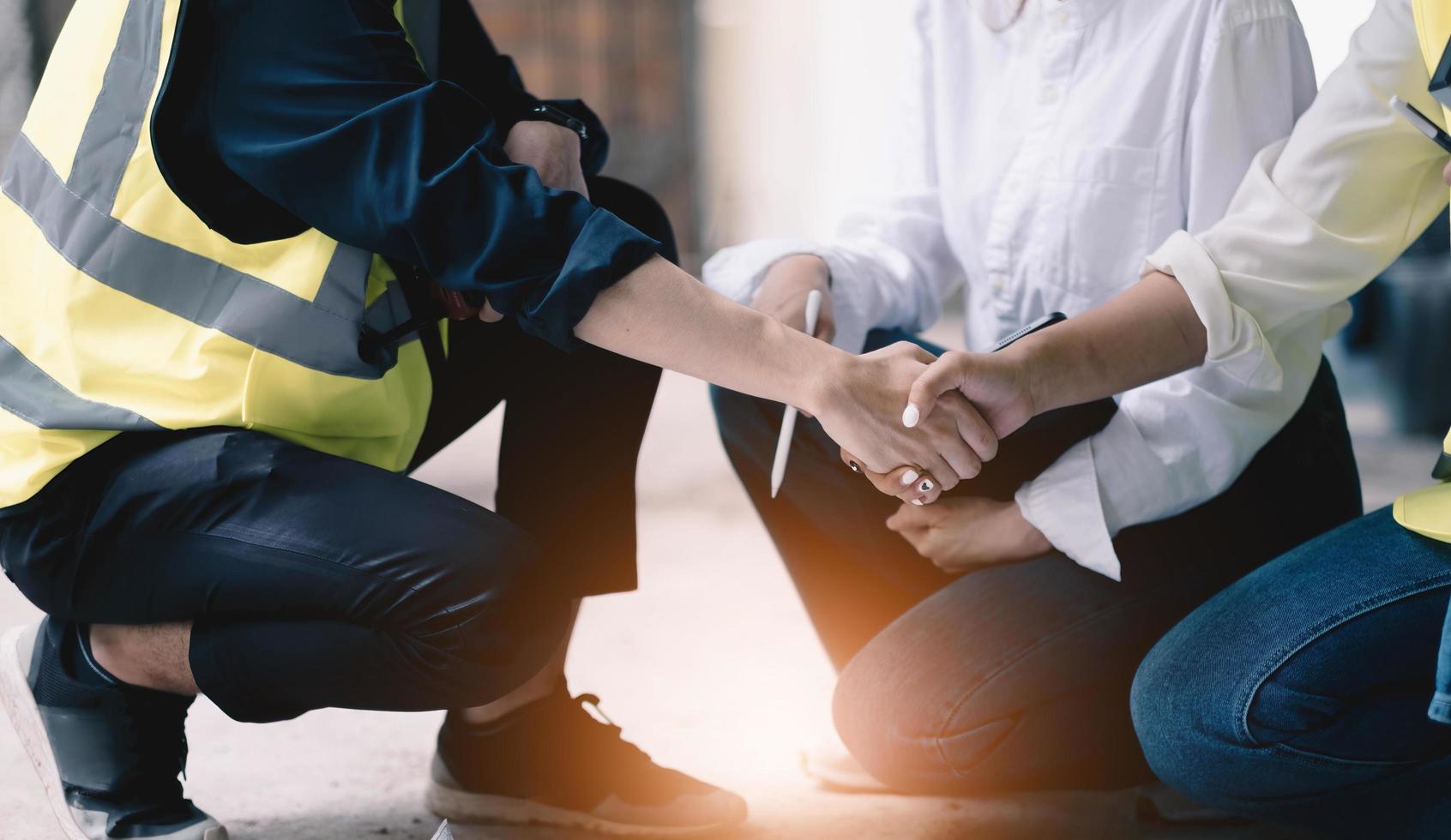 Ingeniero civil masculino o arquitecto apretón de manos con el contratista después de discutir sobre el diseño de estilos de construcción e inspeccionar el progreso del proyecto de vivienda en los sitios de construcción. trabajo de trabajador en bienes raíces foto