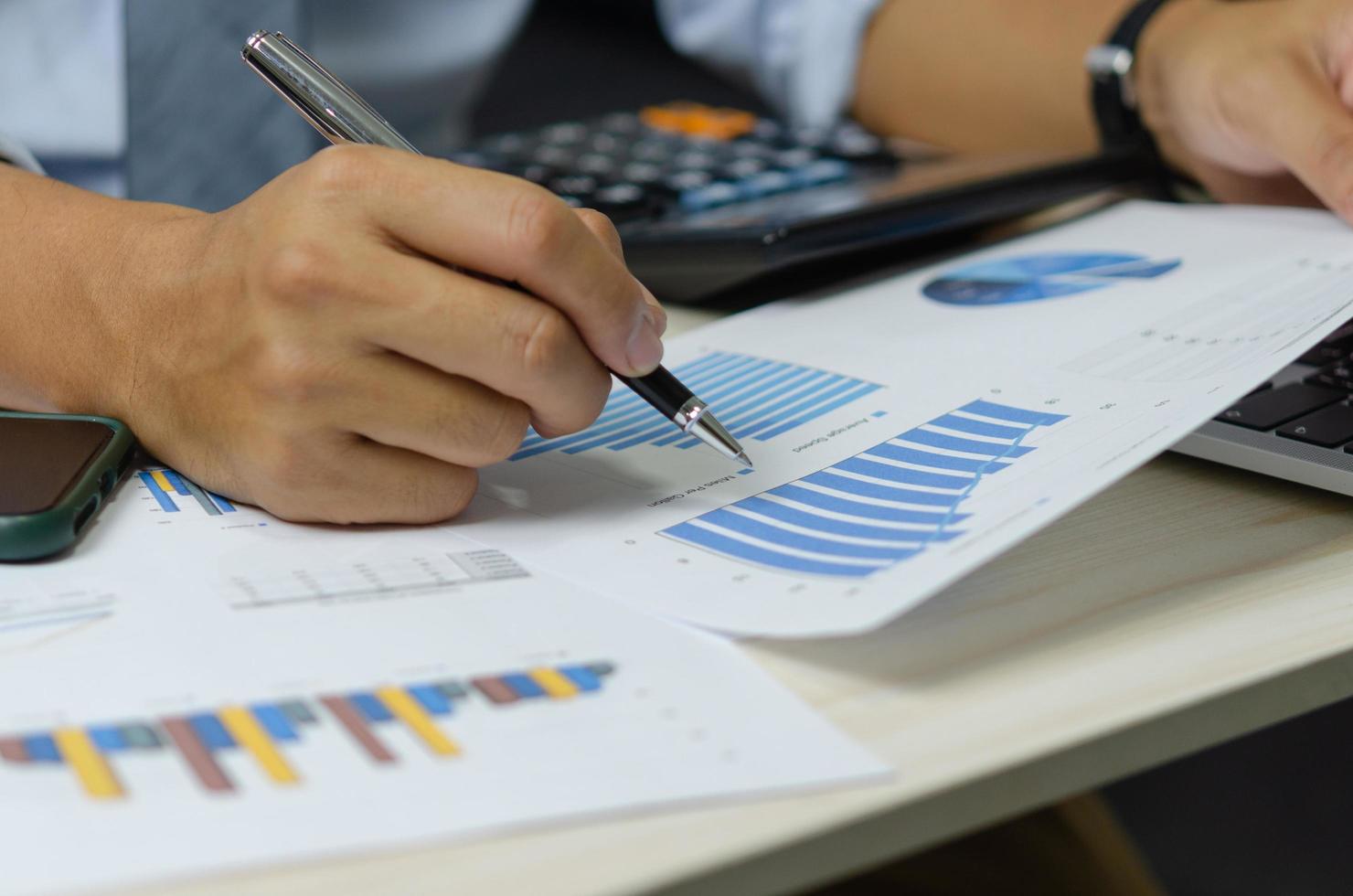businessman holding pen to work computer graphs and charts data statistical data financial analysis documents. photo