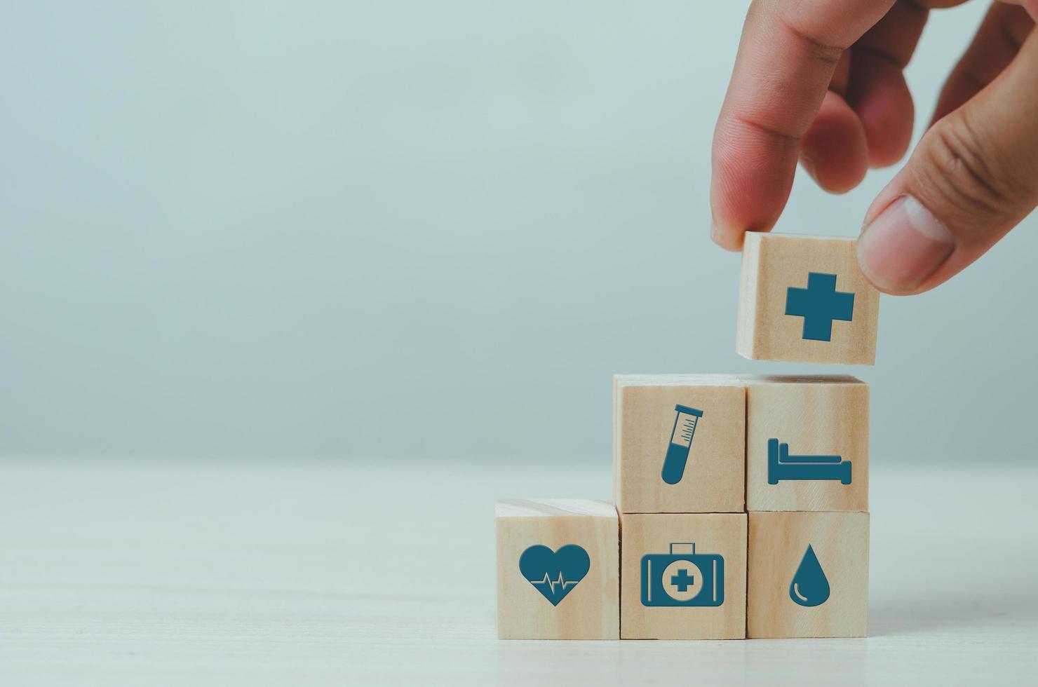 Hand put wooden cubes with insurance health care medical symbol on table copy space.Business concepts. photo