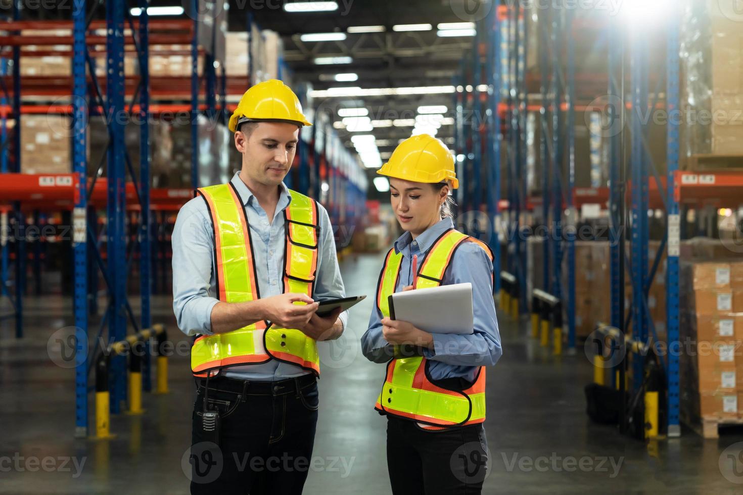 Male and Female Supervisors Holding Digital Tablet Talk about Inventory Check and Product Delivery in Retail Warehouse full of Shelves with Goods. Workers in Logistics Center. photo