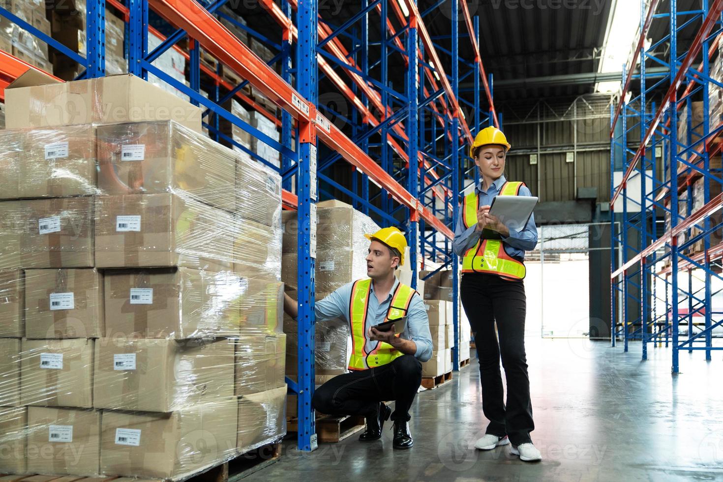 Male and Female Supervisors Hold Digital Tablet is checking the number of items in the warehouse that he is responsible for. checking goods in a warehouse by scanning a barcode. photo