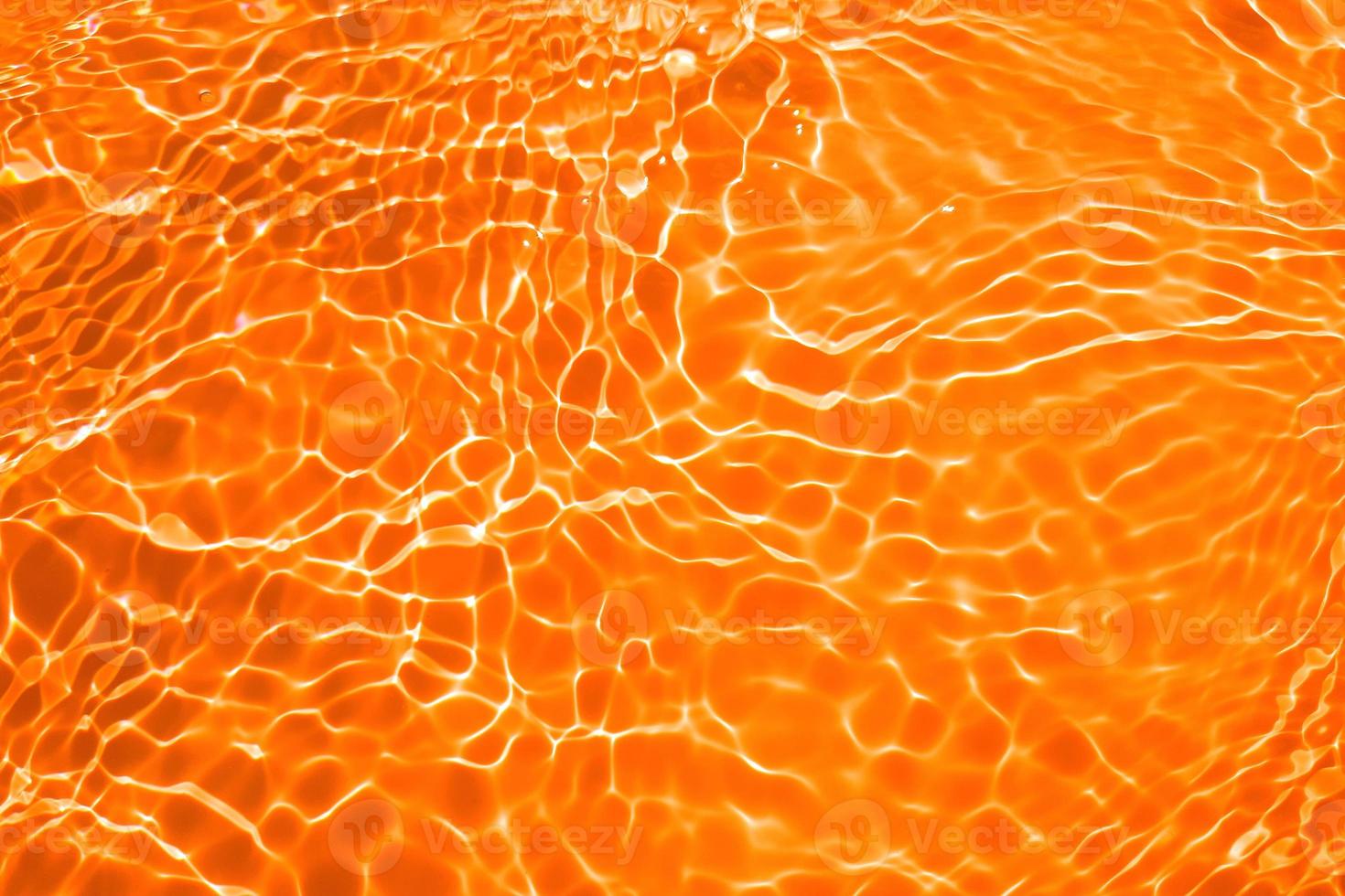 Defocus blurred transparent orange colored clear calm water surface texture with splashes and bubble. Trendy abstract nature background. Water wave in sunlight with copy space. Blue watercolor texture photo