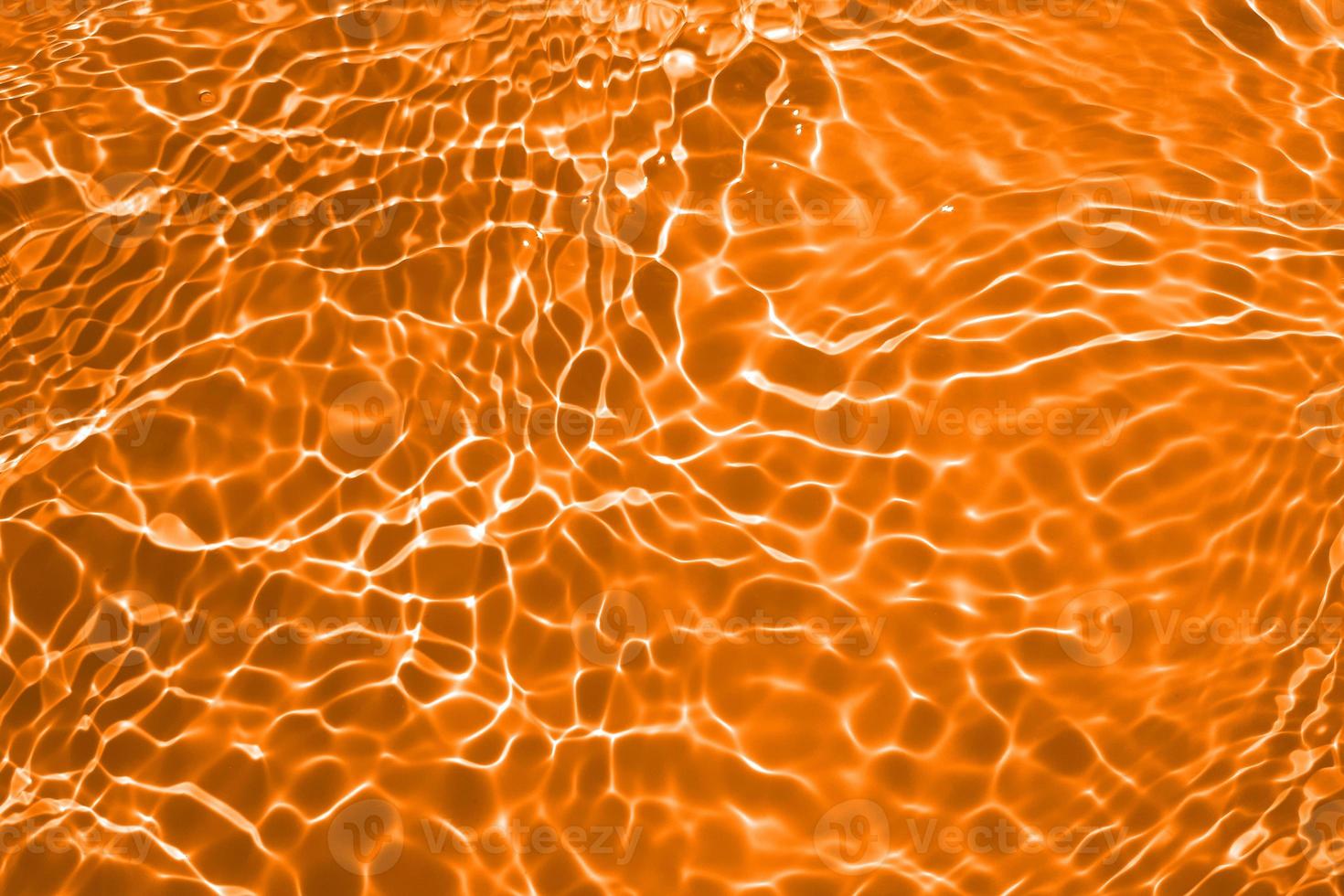 Defocus blurred transparent orange colored clear calm water surface texture with splashes and bubble. Trendy abstract nature background. Water wave in sunlight with copy space. Blue watercolor texture photo