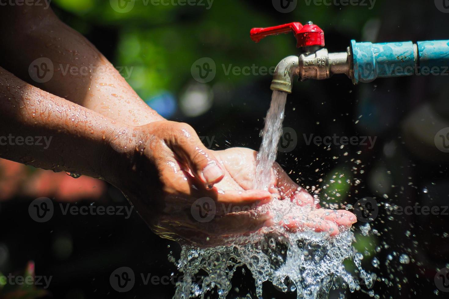 Water concept in everyday life. Hands supporting the water flowing from the faucet. water splashing from the tap photo